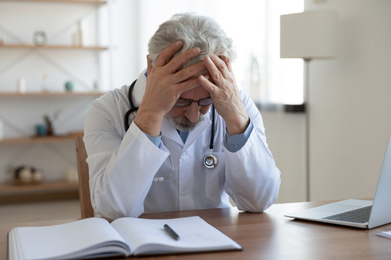 Tired depressed male doctor feels desperate thinking of problem